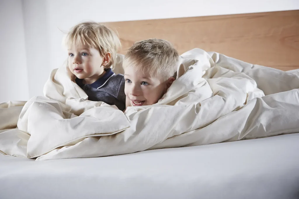 zwei Kinder liegen in einem SAMINA Bett