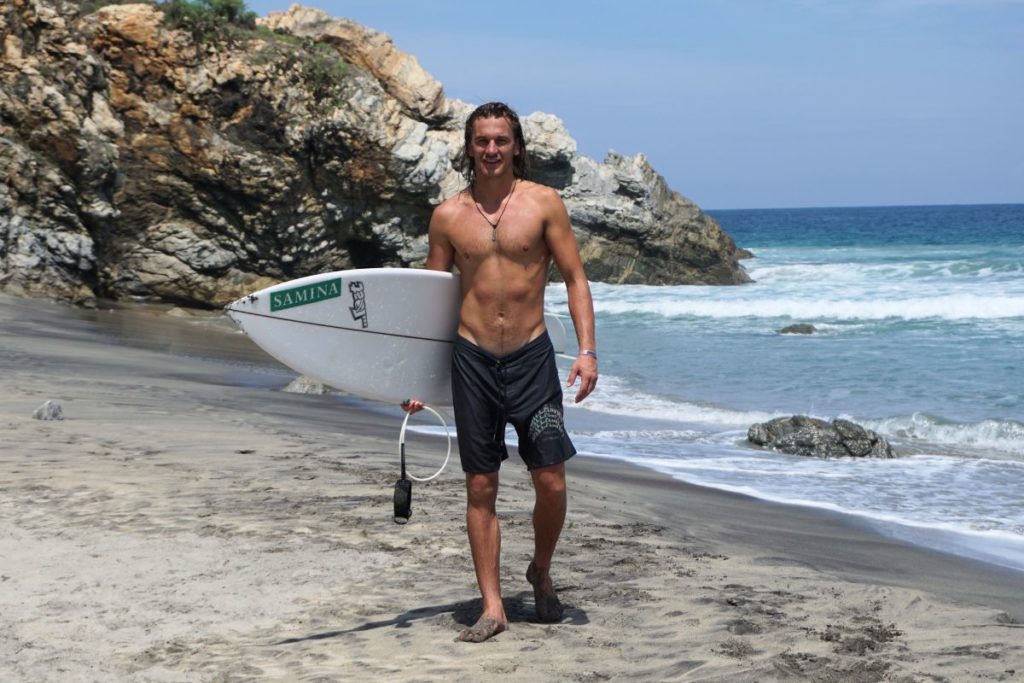 Manuel Paulitsch mit Surfbrett am Strand
